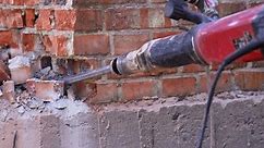 Break up, professional worker drills old brick tube with jackhammer, close up shot.