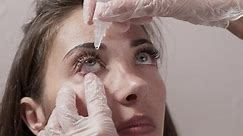 Close-up attentive optometrist dripping eye drops into the patient's eyes. Optometrist during an examination in a modern clinic