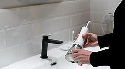 Effortless Oral Health: Woman Filling Water Flosser Tank at Bathroom Basin