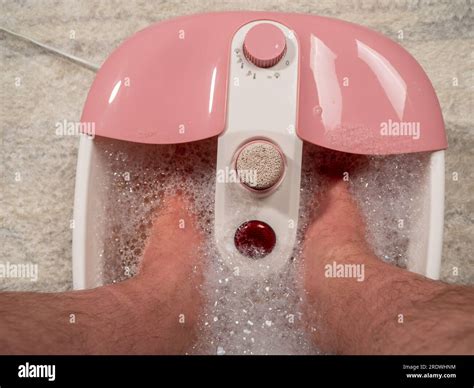 Men's legs in a vibrating foot massager. Electromassage foot bath ...