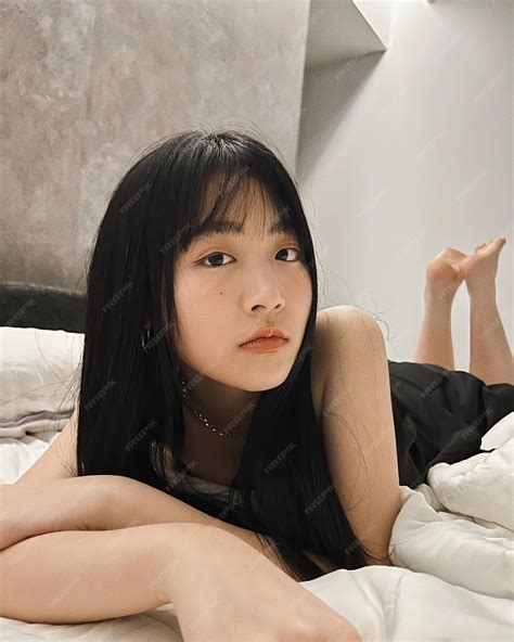 A girl laying in bed with a white sheet on her chest | Premium AI ...