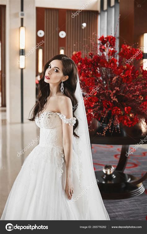 Young sexy bride with perfect body and big breasts in the fashionable wedding dress and in big ...