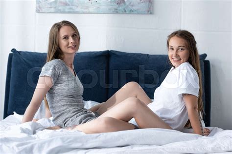 two smiling lesbians sitting on bed in morning and looking at camera | Stock image | Colourbox