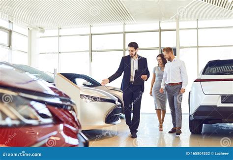 Couple and the Dealer Selling Cars Look the Car in the Showroom. Stock ...