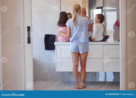 Rear View of a Young Caucasian Mother in Pyjamas Standing with Her ...