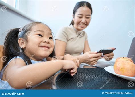 Woman and Girl Sitting at Table with Gadgets and Fruits Stock Photo ...