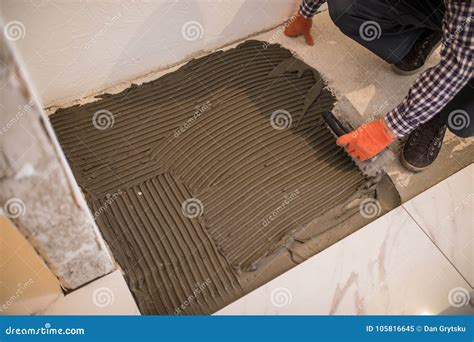Laying Ceramic Tiles. Troweling Mortar Onto a Concrete Floor in ...