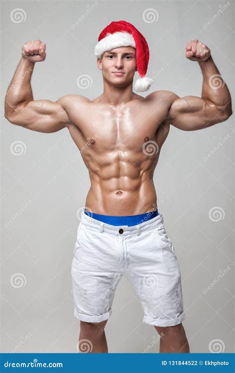 Muscular Naked Guy With A Naked Torso In A Hat Santa Claus Shows Biceps ...