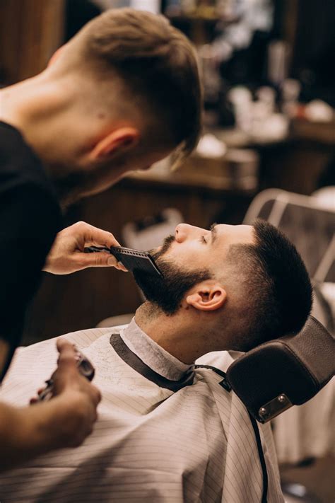 Free Photo | Man at a barbershop salon doing haircut and beard trim ...