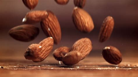 Almonds, a natural ingredient, are cascading onto a wooden table. This ...