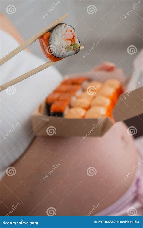 A Pregnant Woman Sits on the Sofa and Eats Rolls from a Box. Food Delivery. Close Up of Belly ...