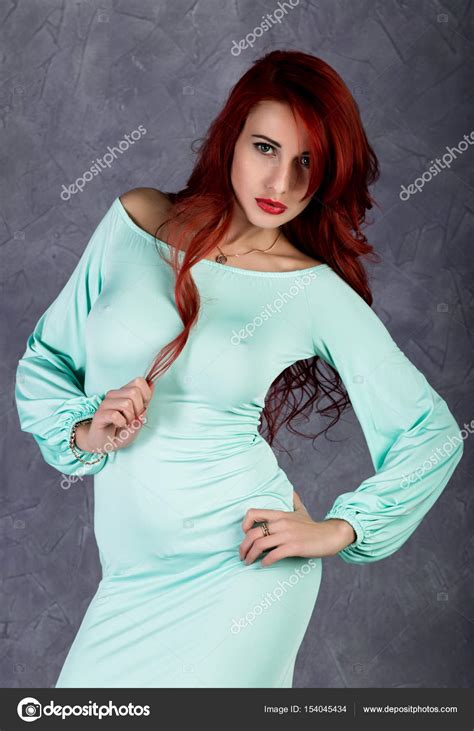 Portrait of beautiful redhead young woman with big boobs in a turquoise ...