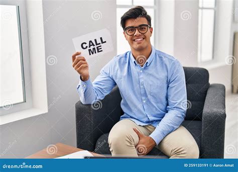 Hispanic Man Working at Therapy Office Holding Call Me Banner Looking ...