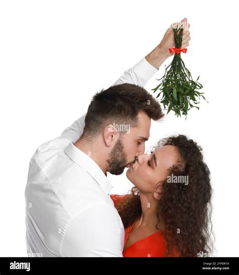 Happy couple kissing under mistletoe bunch on white background Stock Photo - Alamy