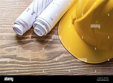 Rolled engineering drawings hard hat on wooden board construction ...