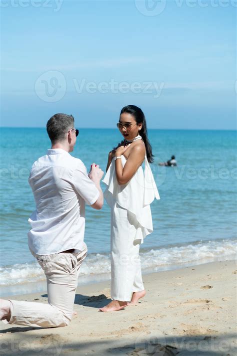 A young white man Asking for an Asian girl to marry with a diamond ring on a beach 14323489 ...