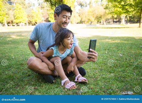 Asian Dad and Little Daughter Resting in Park with Smart Phone Stock ...
