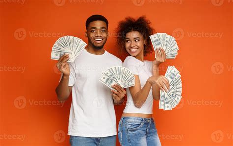 Happy african-american couple holding dollar fans, girl flirt with man ...