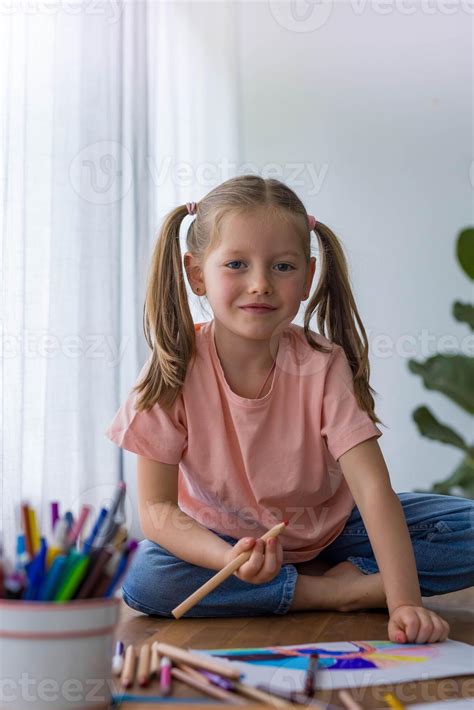 With smile 5-year-old girl giggles while creating art at the table with ...