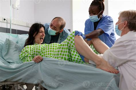 Woman giving birth to child in hospital ward receiving help from ...