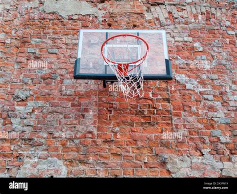 Old and worn outdoor basketball hoop net on the red brick wall ...