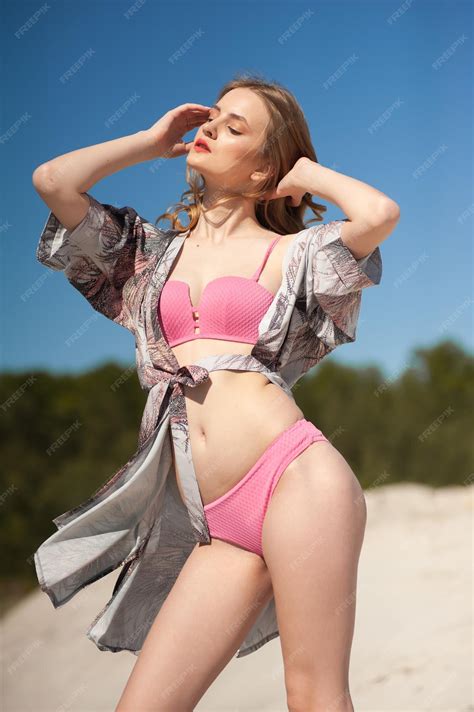 Premium Photo | A girl in a pink bikini poses in front of a blue sky.