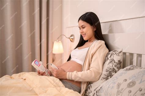 Premium Photo | Beautiful pregnant woman holding pocket fetal doppler to listen babys heartbeat ...