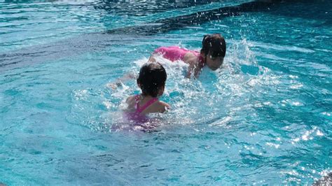 Happy little sisters play in outdoor swimming pool of tropical resort during family summer ...
