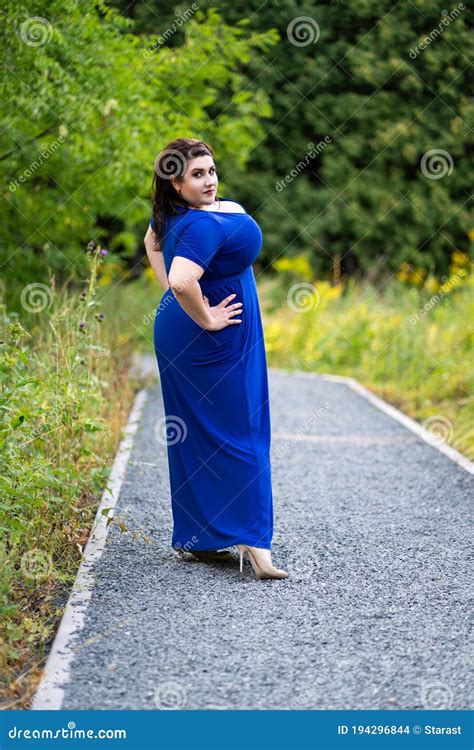 Plus Size Fashion Model in Blue Dress with a Deep Neckline Outdoors ...