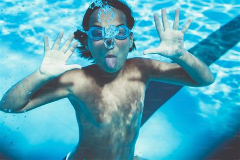 Underwater fun. Cute little girl with goggles swimming underwater and diving in the swimming ...