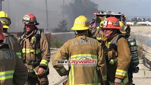 The fire fight continues here in El Monte. An excavator is on scene and is starting to tear apart the structure and the burning contents within. There are mini explosions going off on the backend here near the San Gabriel River. | SGV CityWatch | Facebook