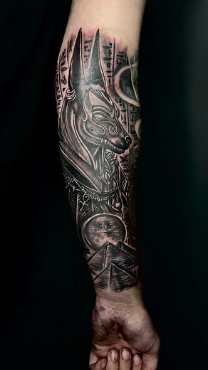 Artist Nine15 Custom Tattoos. An Anubis tattoo, inspired by ancient Egyptian mythology, often features the jackal-headed god Anubis, symbolizing death, afterlife, and protection. Many opt for this design to honor heritage, express a fascination with Egyptian culture, or signify a personal connection to life and death. The tattoo typically showcases Anubis in a powerful stance, holding the ankh or scales of justice, highlighting his role as a guardian of the deceased. The intricate linework and h