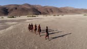 4K aerial zoom out view of people from the Himba tribe walking in the...