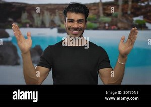 Hispanic man wearing black shirt shows wide hand gesture poolside at resort outdoor pool area; friendliness Stock Video Footage - Alamy