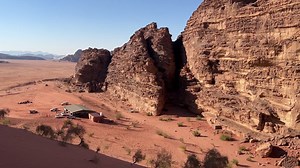 A wide establishing shot of the vast red desert sand of Wadi Rum, with a bedouin camp in Jordan 4K stable shot | Premium Stock Video Footage