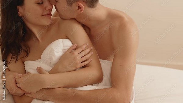 Intimate moment capturing a loving couple embracing on a bed, exuding warmth, affection, and comfort in a private bedroom.