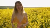 Portrait d’une femme gaie dans un champ de colza avec des fleurs...