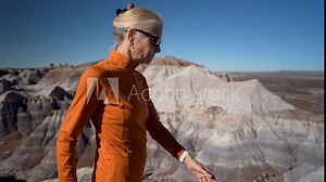Mature woman hikes in Blue Mesa at Petrified Forest National Park in Arizona while taking in the view of the landscape around her.