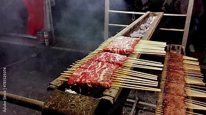 Grilling "arrosticini": Italian specialty of the Abruzzo region of sheep meat skewers. The hands arrange groups of skewers to cook near the burning embers. Italian food and traditions.