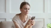 Jealous worried young woman holding phone feeling jealousy anxiety...