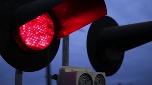 clip-1100783061-railway-crossing-flashing-red-traffic-lights-close-up