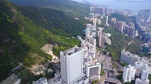 クイーン・メアリー病院から、香港島西側のビクトリアピークの下部にあるサンディ湾までの空撮パン。山間部に混在する森林地帯と密集した建築地帯を持つ曲線ポックフラムロード