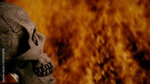 A scary human skull (on the left side), rotating on its axis, over a fire pyre with wild flames in the dark night.