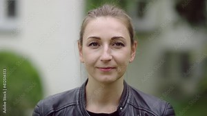 Face of mid-thirties blonde woman in the garden who is gently smiling.