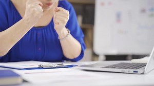 Angry businesswoman banging fist, table.
