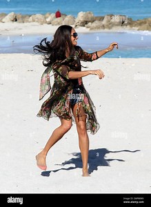 After filming a video for her new song "Every Part Of Me", British songbird, Alesha Dixon, shows off some of her curves in a one piece bathing suit, denim hotpants and a floral coverup and plays a game of Volley Ball with pals. Miami Beach, FL. 12/15/10 Stock Photo - Alamy