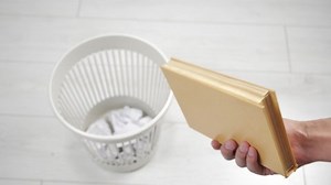 Throwing away book into trash bin. Outdated literature.