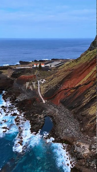 Bare mount of diverse colors at the shore of the Azorean Islands, the Autonomous Region of the Azores. Drone footage approaching the road leading to the cottage. Vertical video.