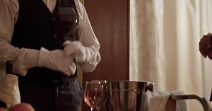 Crop room service waiter showing wine and fruits served on trolley to guest