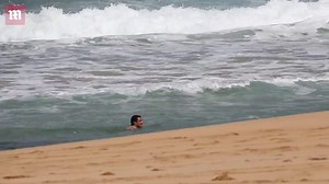 Katy Perry frolics in the ocean in a purple strapless swim suit